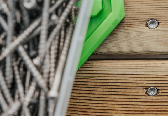 A box of ESSDECK Max decking screw on a wood deck.